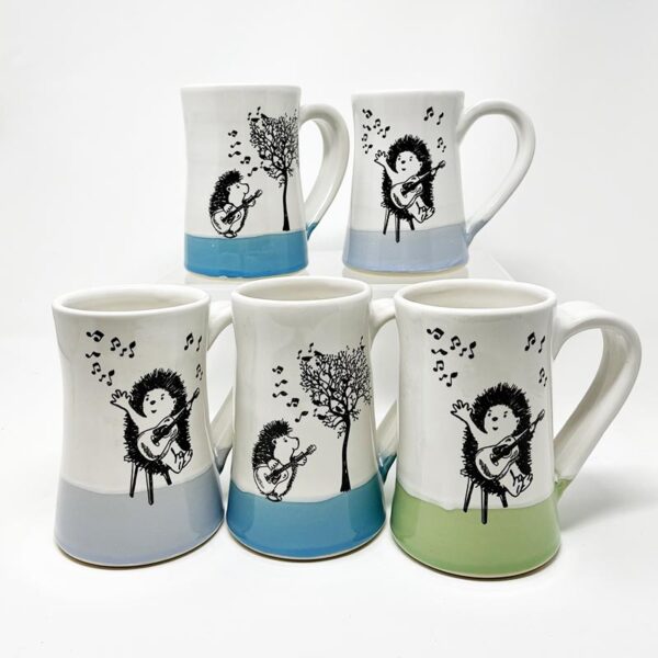 five handmade ceramic mugs with drawings of hedgehogs playing guitar and ukelele