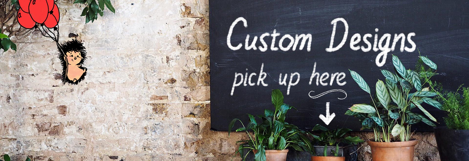 A chalkboard on a brick wall with text "Custom Designs"